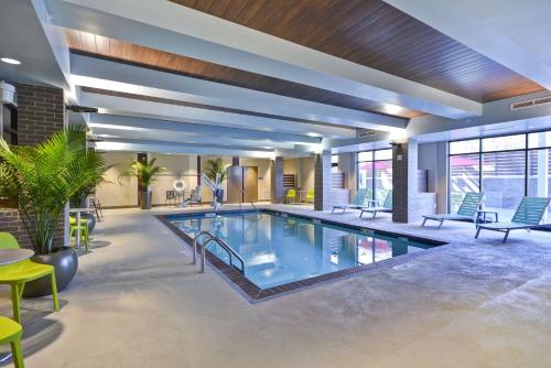 a pool in a hotel room with tables and chairs at Home2 Suites by Hilton Kansas City KU Medical Center in Kansas City
