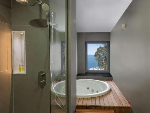 a bathroom with a bath tub and a window at DoubleTree by Hilton Antalya-Kemer All-Inclusive Resort in Kemer
