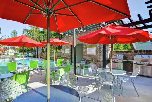 a patio with tables and chairs with red umbrellas at Home2 Suites By Hilton Hilton Head in Hilton Head Island