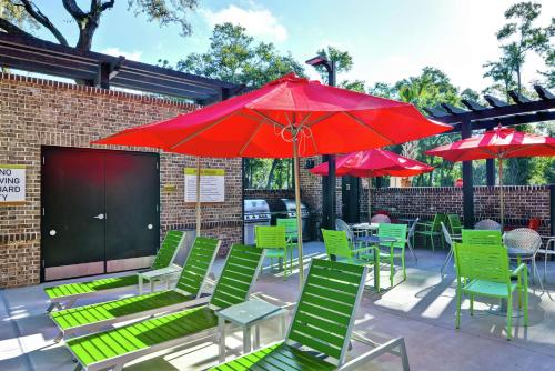 a patio with green chairs and red umbrellas at Home2 Suites By Hilton Hilton Head in Hilton Head Island