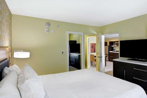 a bedroom with a white bed and a flat screen tv at Home2 Suites By Hilton Hilton Head in Hilton Head Island