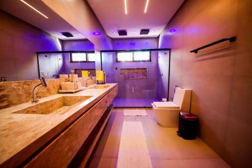 a bathroom with a sink and a toilet and purple lights at Casa Ofir - Alto Padrão in Praia do Forte
