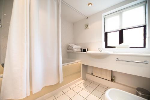 a white bathroom with a shower curtain and a sink at The Groes Inn in Conwy