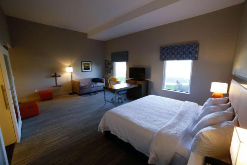 a hotel room with a bed and a living room at Hampton Inn & Suites Forest City in Forest City