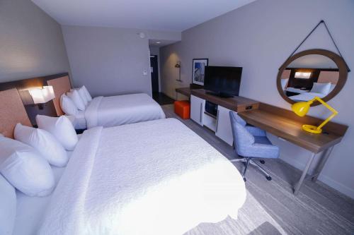 a hotel room with two beds and a desk with a mirror at Hampton Inn & Suites Forest City in Forest City