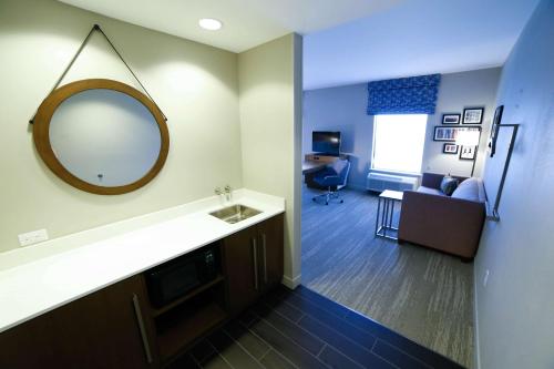 a bathroom with a mirror and a living room at Hampton Inn & Suites Forest City in Forest City