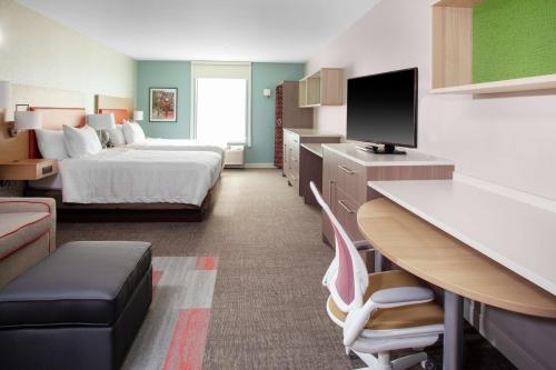 布卢明顿Home2 Suites by Hilton Bloomington的配有床和书桌的酒店房间