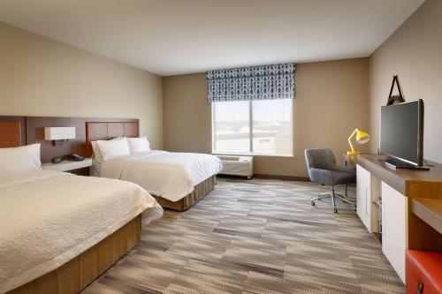 a hotel room with two beds and a flat screen tv at Hampton Inn & Suites Rexburg in Rexburg