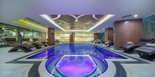 a swimming pool in a hotel lobby with chairs and tables at Hilton Garden Inn Yalova in Yalova
