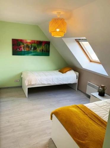une chambre mansardée avec deux lits et une fenêtre dans l'établissement Agréable maison moderne, entre campagne et mer !, à Dozulé