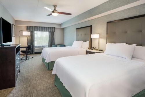 a hotel room with two beds and a flat screen tv at Homewood Suites By Hilton Ottawa Airport in Ottawa