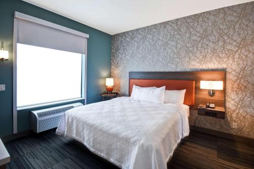 a bedroom with a large bed and a large window at Home2 Suites Mechanicsburg in Mechanicsburg