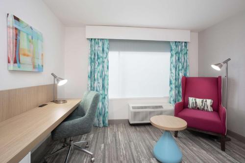 a room with a desk and a chair and a table at Hilton Garden Inn Omaha Aksarben Village in Omaha