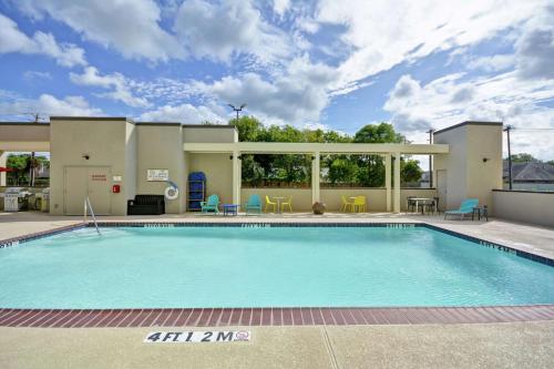 a pool at a resort with chairs and a table at Home2 Suites By Hilton Texas City Houston in Texas City