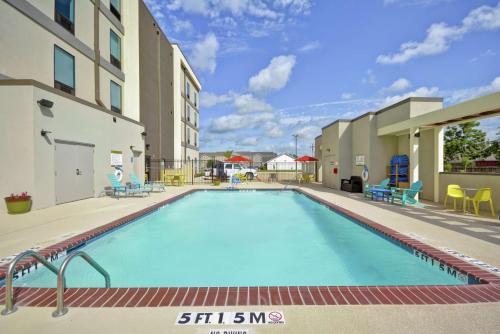 einen Pool in einem Hotel mit Tischen und Stühlen in der Unterkunft Home2 Suites By Hilton Texas City Houston in Texas City