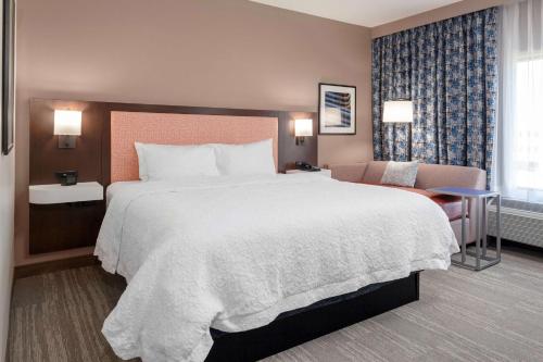 StanleyにあるHampton Inn & Suites Overland Park Southの大きなベッドと椅子が備わるホテルルームです。