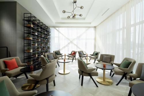 a waiting room with chairs and tables and a large window at Doubletree By Hilton Montreal Airport in Dorval
