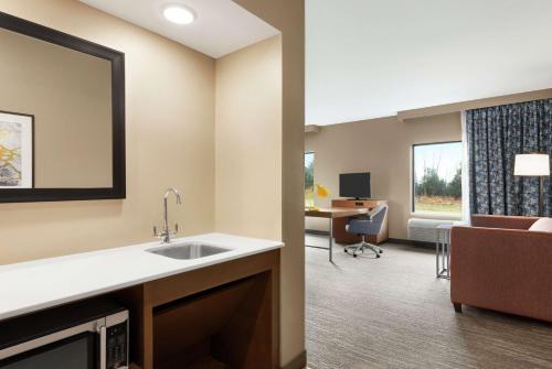 a kitchen with a sink and a living room with a couch at Hampton Inn & Suites Overland Park South in Stanley