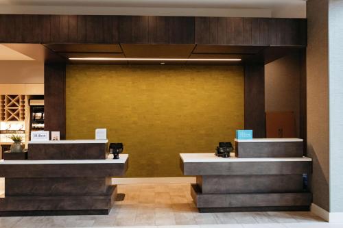 a lobby with two reception desks and a yellow wall at Hilton Garden Inn Madison Sun Prairie in Sun Prairie