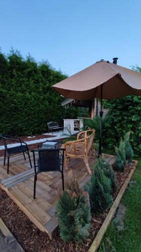 a wooden deck with two chairs and an umbrella at Saviaugu majake Põlvamaal in Kärsa