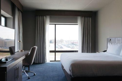 a hotel room with a bed and a desk and a window at Hilton Garden Inn Madison Sun Prairie in Sun Prairie