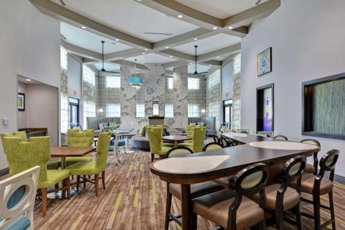 a dining room with tables and chairs and windows at Homewood Suites By Hilton Savannah Airport in Savannah