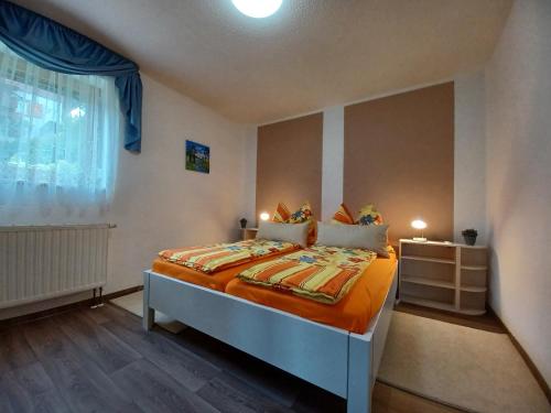 um quarto com uma cama com lençóis laranja e uma janela em Haseltal em Suhl