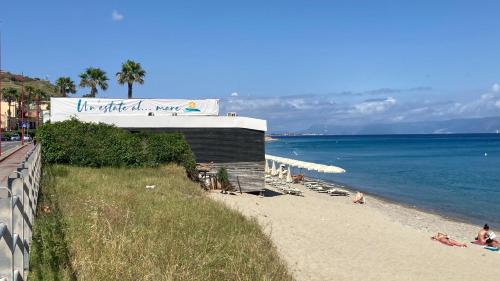 a beach with people sitting on the sand and the ocean at Three Rooms in Messina