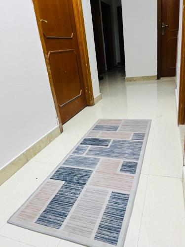 a hallway with a rug on the floor in front of a door at Near Alain Main Bus stop in Mundafinah