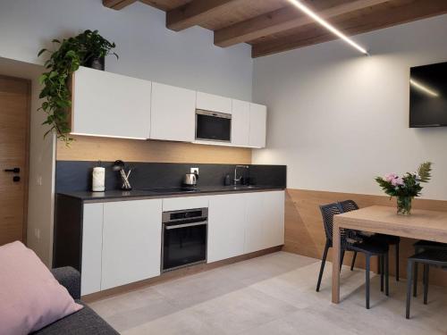 uma cozinha com armários brancos e uma mesa com cadeiras em Magnolia Levico em Levico Terme