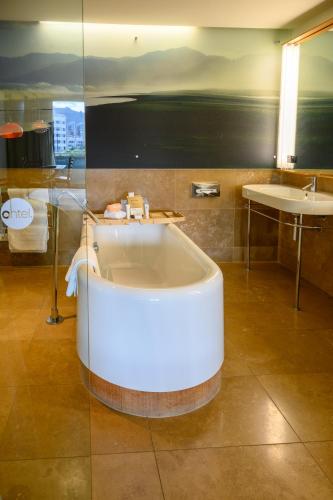 a bath tub in a bathroom with a sink at Ohtel Wellington in Wellington