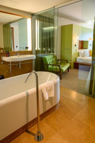 a bathroom with a bath tub and a bedroom at Ohtel Wellington in Wellington
