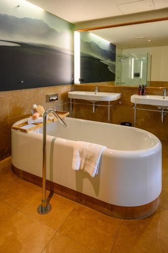 a bath tub in a bathroom with two sinks at Ohtel Wellington in Wellington