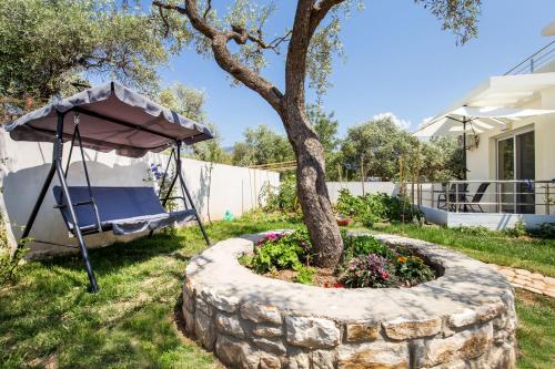 a garden with a tree and an umbrella at Otium Studios in Limenaria
