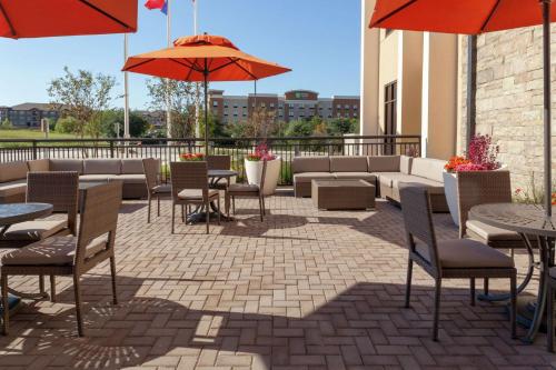 an outdoor patio with tables and chairs and umbrellas at Hilton Garden Inn Waco in Waco