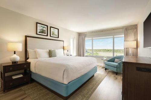 ein Schlafzimmer mit einem großen Bett und einem blauen Stuhl in der Unterkunft Hotel Ballast Wilmington, Tapestry Collection by Hilton in Wilmington