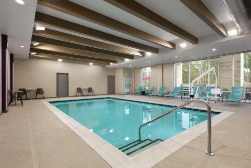 a large swimming pool with blue chairs and tables at Home2 Suites By Hilton Columbia Harbison in Columbia