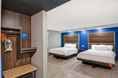 Tru by Hilton Syracuse North Airport Area في ليفربول: غرفة فندق بسريرين وجدران زرقاء