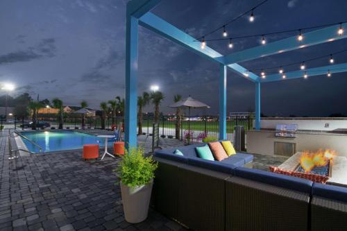 a patio with a fire pit and a pool at night at Tru by Hilton Lafayette River Ranch in Lafayette