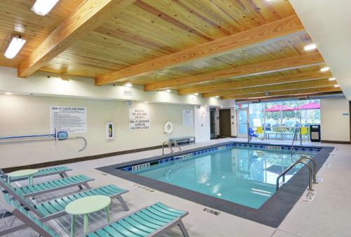 a swimming pool with chairs and a table and a tablektop at Home2 Suites By Hilton Richmond Hill Savannah I-95 in Richmond Hill