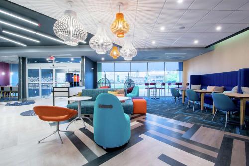 a lobby with tables and chairs and windows at Tru by Hilton Lafayette River Ranch in Lafayette