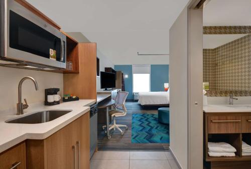 a kitchen with a sink and a room with a bed at Home2 Suites By Hilton Richmond Hill Savannah I-95 in Richmond Hill