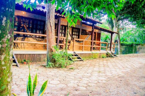 a wooden house with a porch in front of it at Chalé 03 Itaipu Vale da Colina Niterói in Niterói