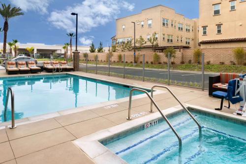 a swimming pool with chairs and a building at Hampton Inn & Suites Buena Park in Buena Park