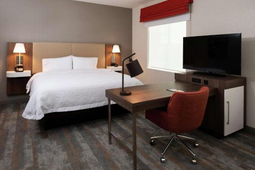 a hotel room with a bed and a desk and a television at Hampton Inn & Suites Buena Park in Buena Park