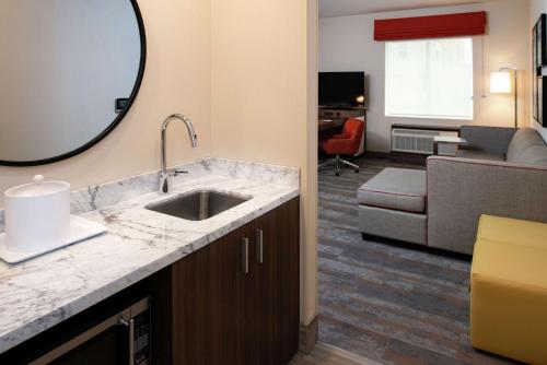 a bathroom with a sink and a living room at Hampton Inn & Suites Buena Park in Buena Park