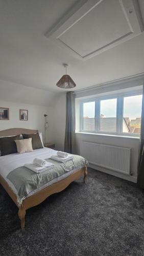 a bedroom with a bed and a large window at The Cowshed, SAV - Romney Sands Beach House in Littlestone-on-Sea