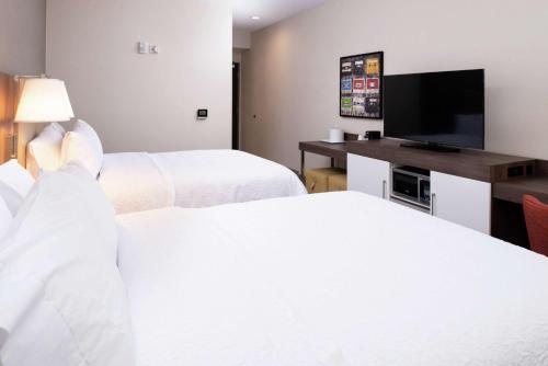 a hotel room with two beds and a flat screen tv at Hampton Inn & Suites Buena Park in Buena Park