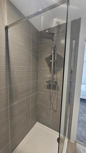 a bathroom with a shower with a glass door at The Cowshed, SAV - Romney Sands Beach House in Littlestone-on-Sea