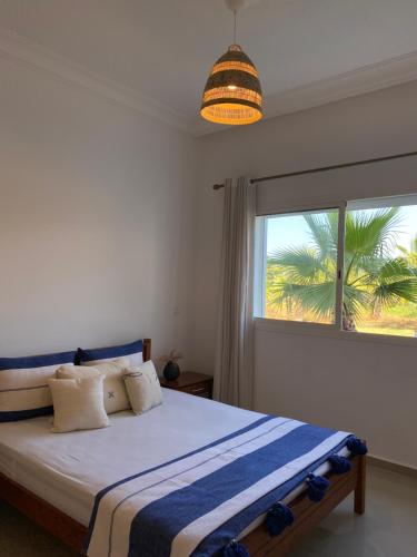 a bedroom with a bed and a window with a palm tree at Asilah marina golf in Asilah